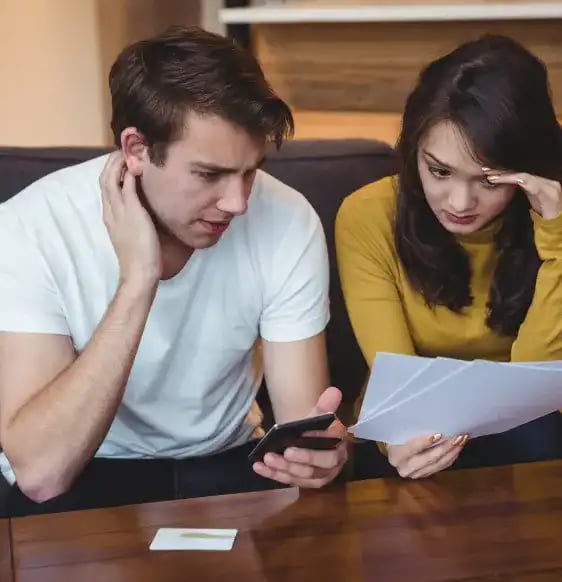 Stressed out couple holding paperwork.